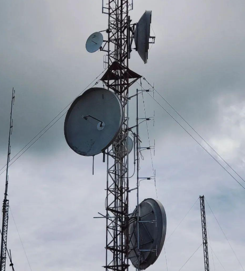 Communications tower with dish and panel antennas.