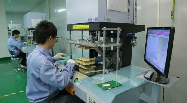 Operator using a PCB test fixture and computer workstation.
